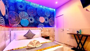 A modern bedroom with a large bed, a decorative wall mural, and a small bedside table with a bottle. - Bed Cinecittadue (Rome)