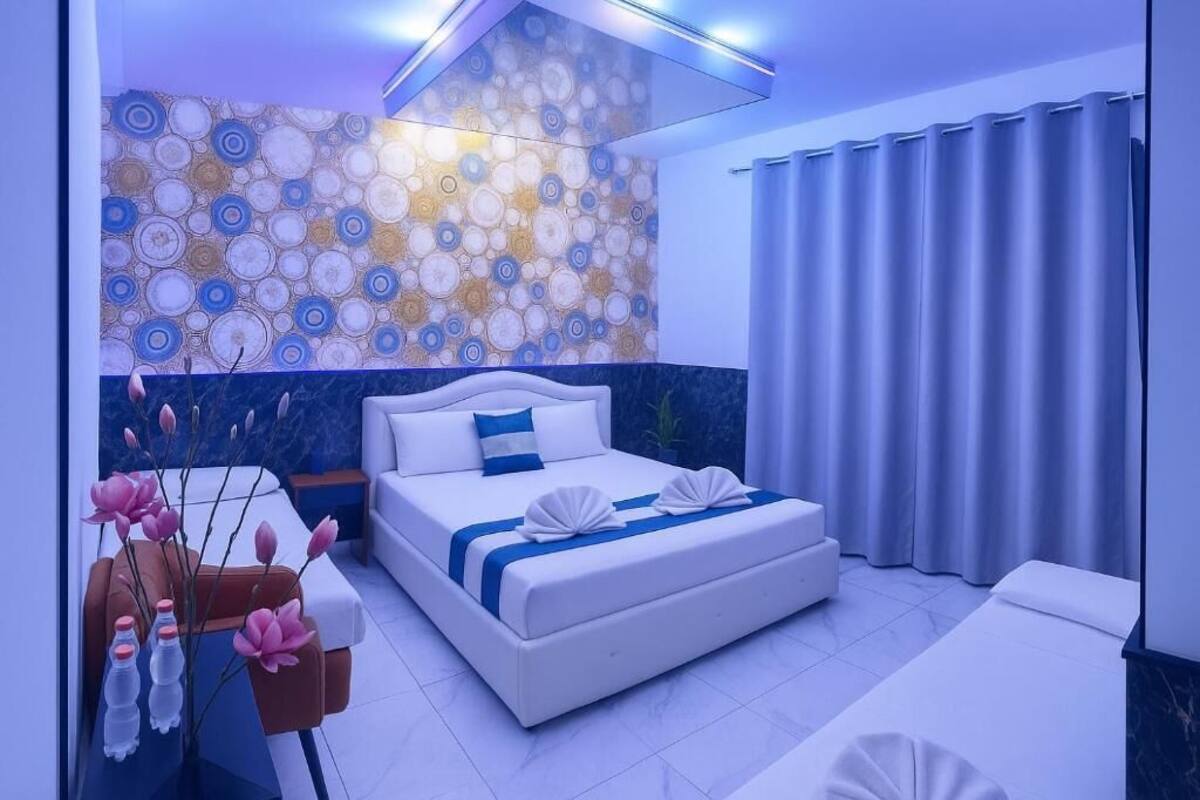A modern hotel room with a large bed, a seating area, and a decorative wall.