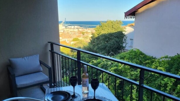 Un balcon avec une table dressée pour deux personnes, une bouteille et deux verres à vin.