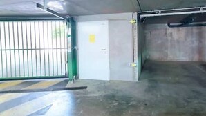 Un parking avec une barrière verte, une porte blanche et des murs en béton.