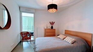 Une chambre à coucher comprenant un lit, une commode, une chaise et un luminaire suspendu.