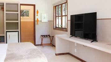A hotel room with a bed, a TV on a stand, a wardrobe, and a window with a view of greenery.