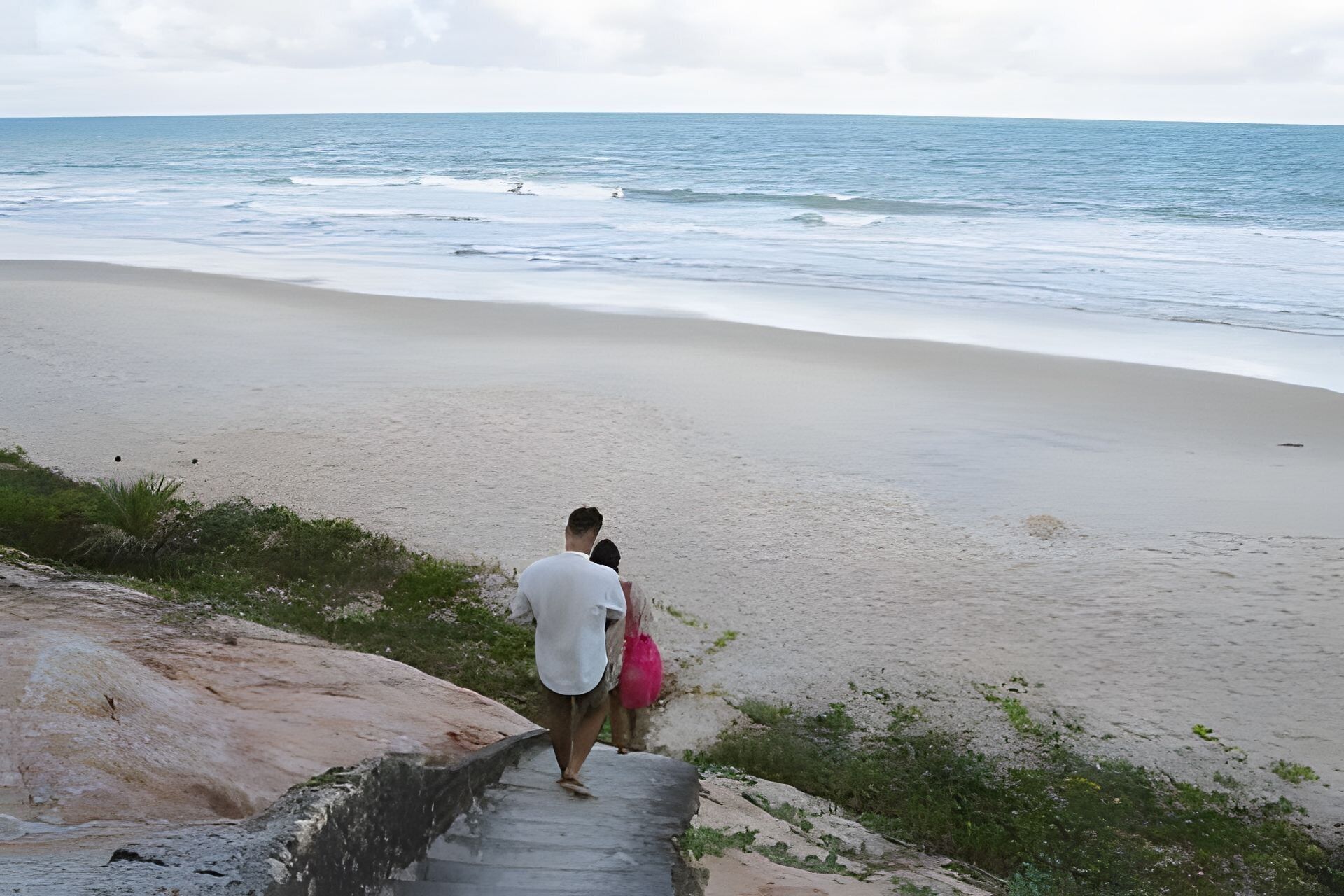 A beach with a concrete path leading to the shore.