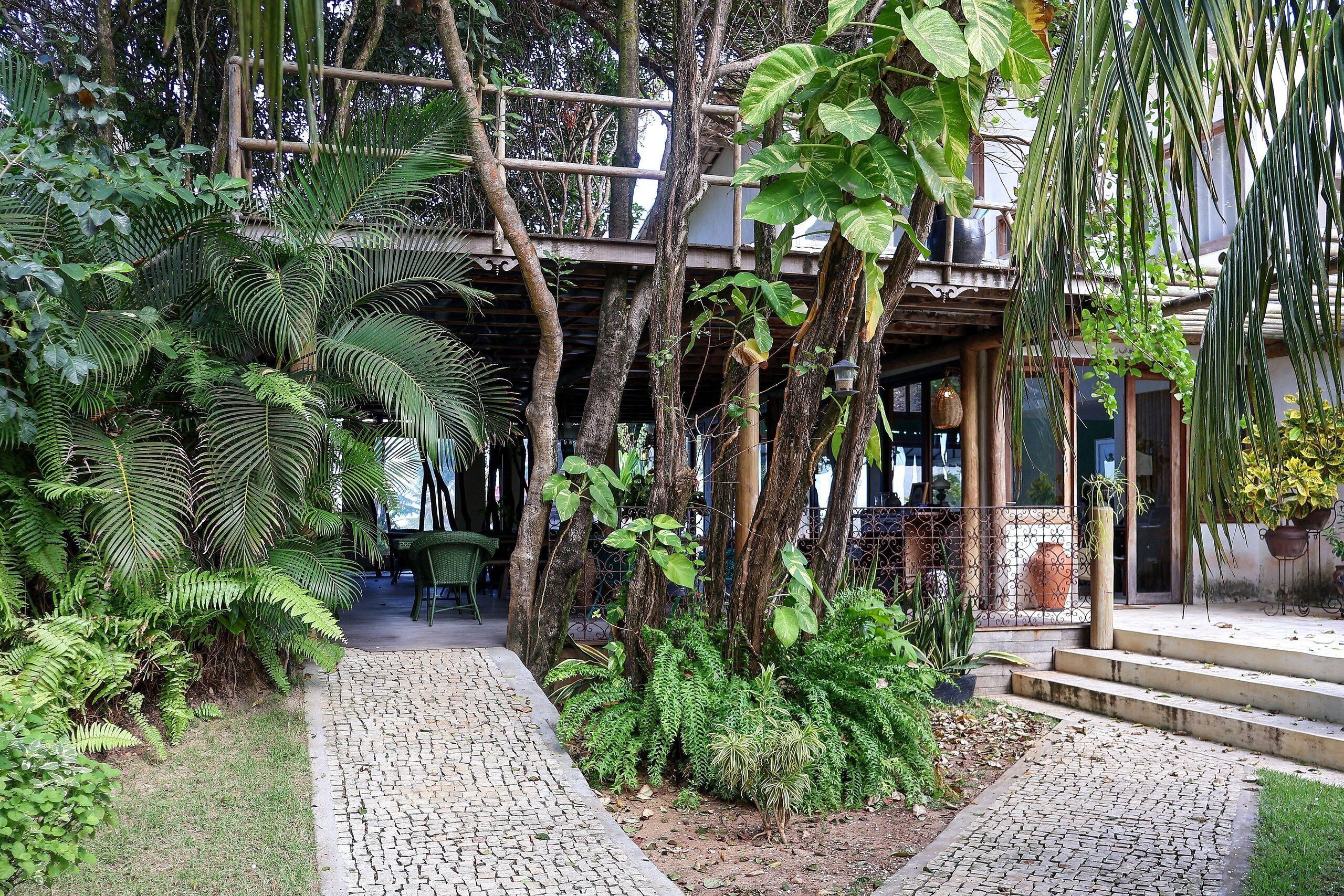 A garden pathway leading to a building with a wooden structure overhead.
