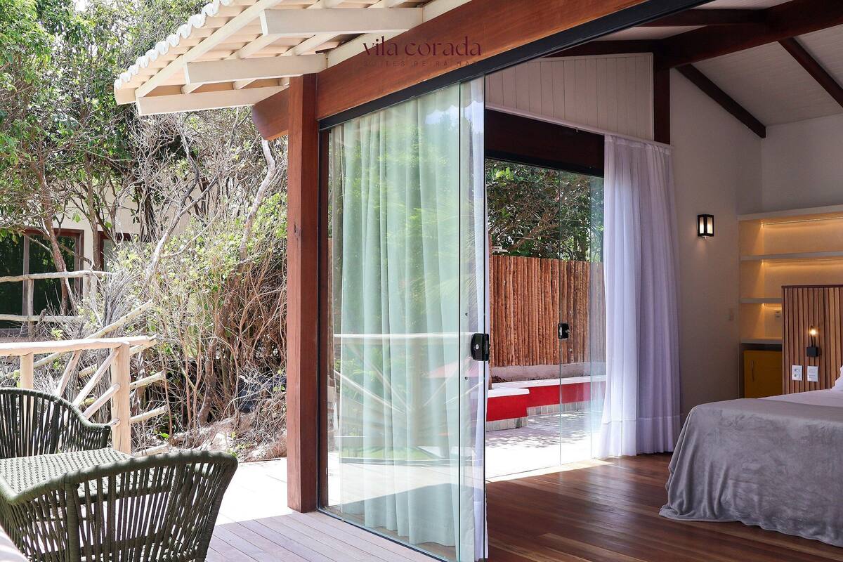 A room with a bed, a sliding glass door leading to an outdoor area with a wooden deck and chairs.