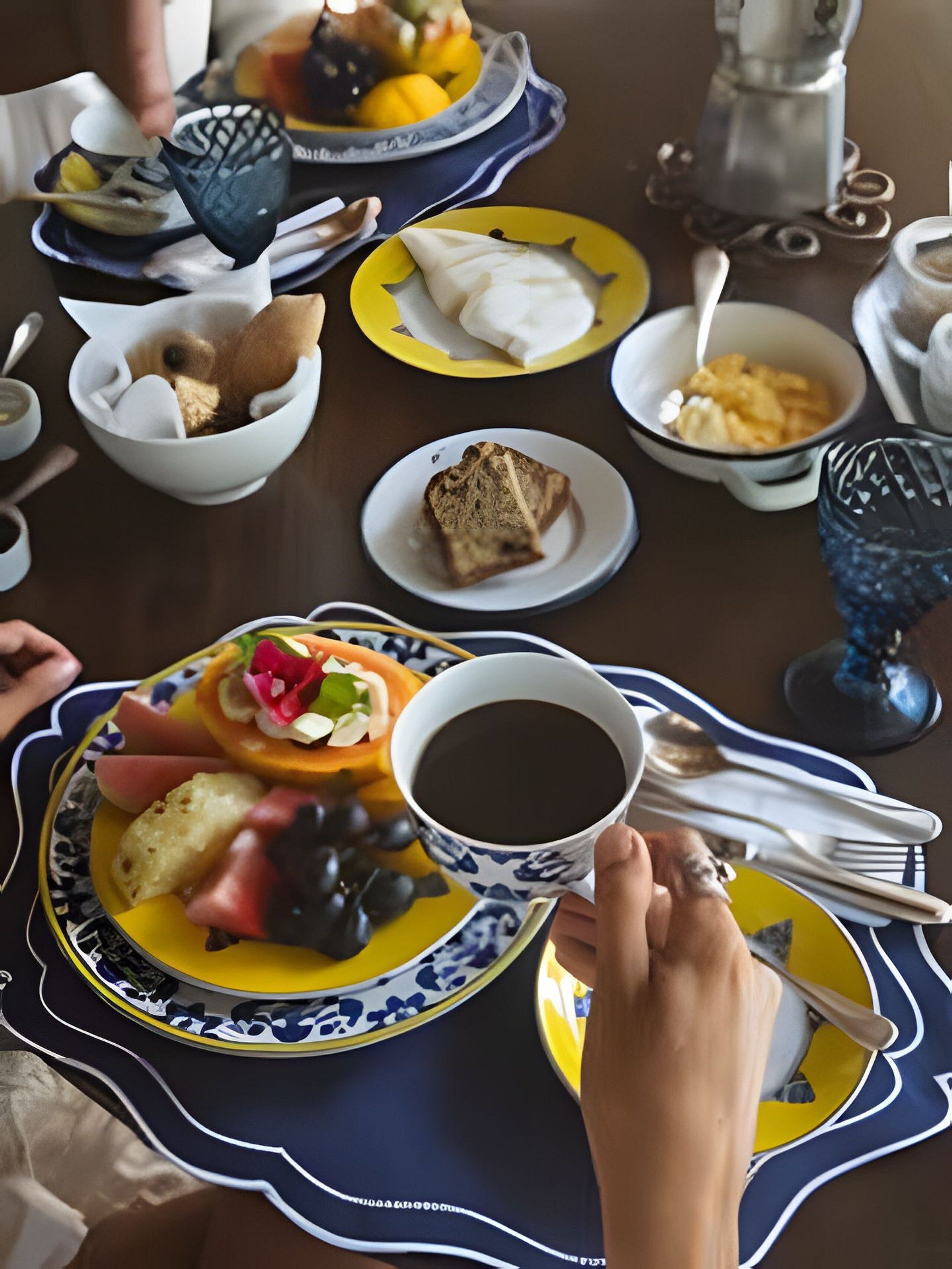 Ein Esstisch mit verschiedenen Speisen, darunter ein Teller mit einer Kaffeetasse, eine Suppenschüssel und ein Teller mit einem Sandwich und Gemüse.