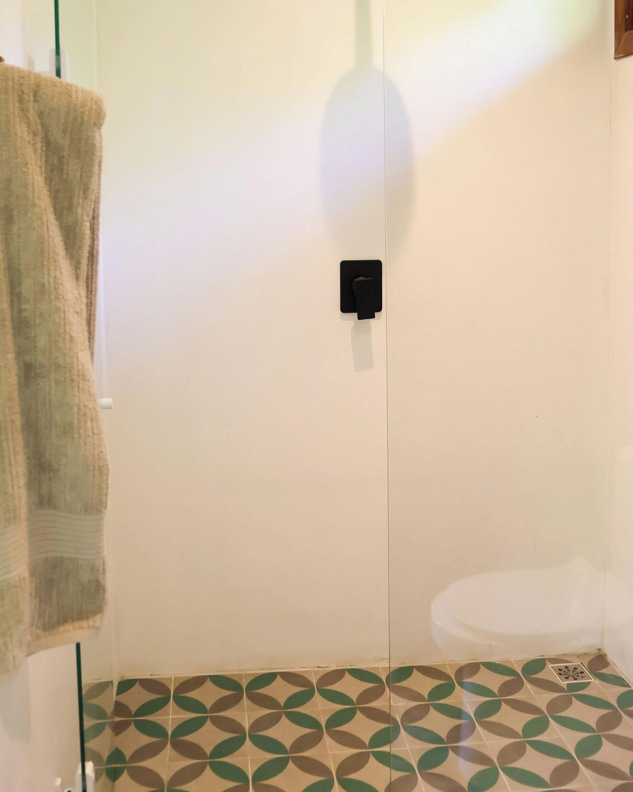 Une salle de bain avec des toilettes, une serviette accrochée au mur et des carreaux de sol à motifs.