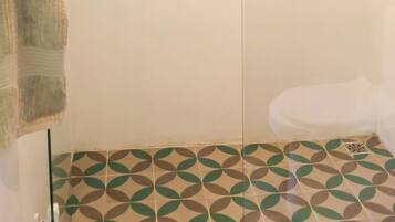 Une salle de bain avec des toilettes, une serviette accrochée au mur et des carreaux de sol à motifs.