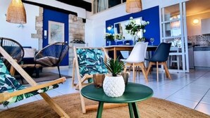 A modern living room with a green table, wicker chairs, and a blue accent wall. - Le Tassigny Duplex Superbe Vue sur les Quai Centre (Sète)