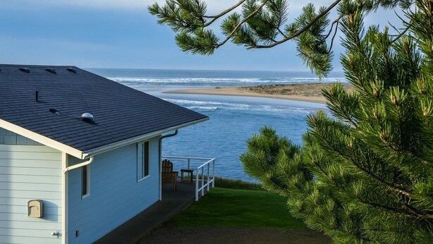 Ett hus med en balkong med utsikt över en strand och havet.