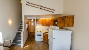 A kitchen with wooden cabinets, a stove, and a refrigerator. - Cahilty #308 Hotel Room (Sun Peaks)