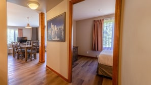 A hotel room with a bed, a desk, and a dining area with chairs.