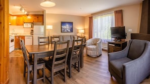 A cozy living room with a dining area, a television, and a kitchen in the background.
