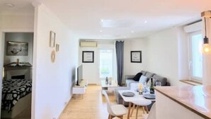 A modern, well-lit living area with a dining table, chairs, and a sofa. - Le Barbusse Coeur de Ville Superbe Déco Climatisé (Sète)