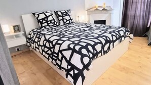 A modern bedroom with a large bed, a bedside table, and a fireplace. - Le Barbusse Coeur de Ville Superbe Déco Climatisé (Sète)