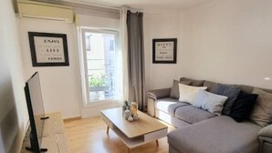 A living room with a grey sofa, a wooden coffee table, and a TV on a stand. There are two framed motivational quotes on the wall. - Le Barbusse Coeur de Ville Superbe Déco Climatisé (Sète)