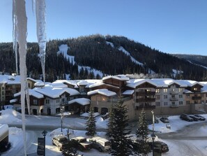 A snow-covered resort with multiple buildings, a ski lift, and a mountainous backdrop. - Cahilty #436 Hotel Room (Sun Peaks)