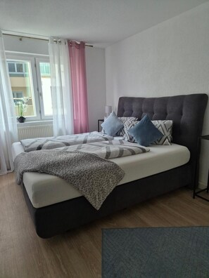 A bed with a dark headboard, multiple pillows, and a leopard print blanket. - Apartment "Ella 1" with Lake View, Balcony and Wi-Fi (Friedrichshafen)