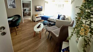 A compact living space with a kitchenette, a sofa, a dining area, and a TV. - Apartment "Ella 1" with Lake View, Balcony and Wi-Fi (Friedrichshafen)