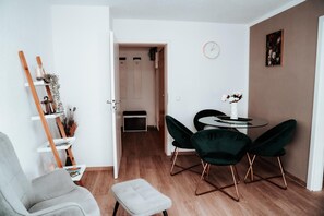 A modern living room with a wooden floor, a grey armchair, a small table with a vase, and a green chair. - Apartment "Ella 1" with Lake View, Balcony and Wi-Fi (Friedrichshafen)