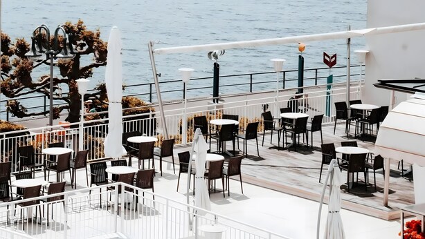 Een terras aan zee met zitplaatsen buiten en uitzicht op de zee.