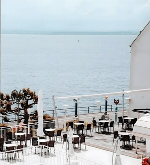 A seaside terrace with outdoor seating and a view of the sea. - Apartment 'Ella 2' with Lake View, Balcony and Wi-Fi (Friedrichshafen)