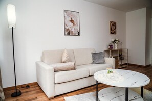 Uma sala de estar minimalista com um sofá, uma mesa de centro redonda e um abajur de chão.