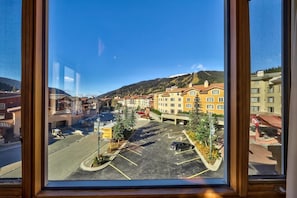 A view of a town with a parking lot, buildings, and a mountain in the background.