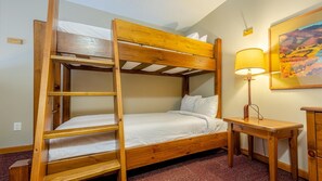 A bunk bed with a ladder, a bedside table, a lamp, and a painting on the wall. - Cahilty #427 Hotel Room (Sun Peaks)