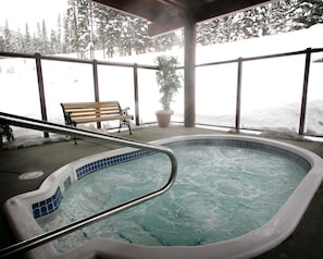 A hot tub with a tiled edge, a wooden bench, and a potted plant. - Cahilty #427 Hotel Room (Sun Peaks)