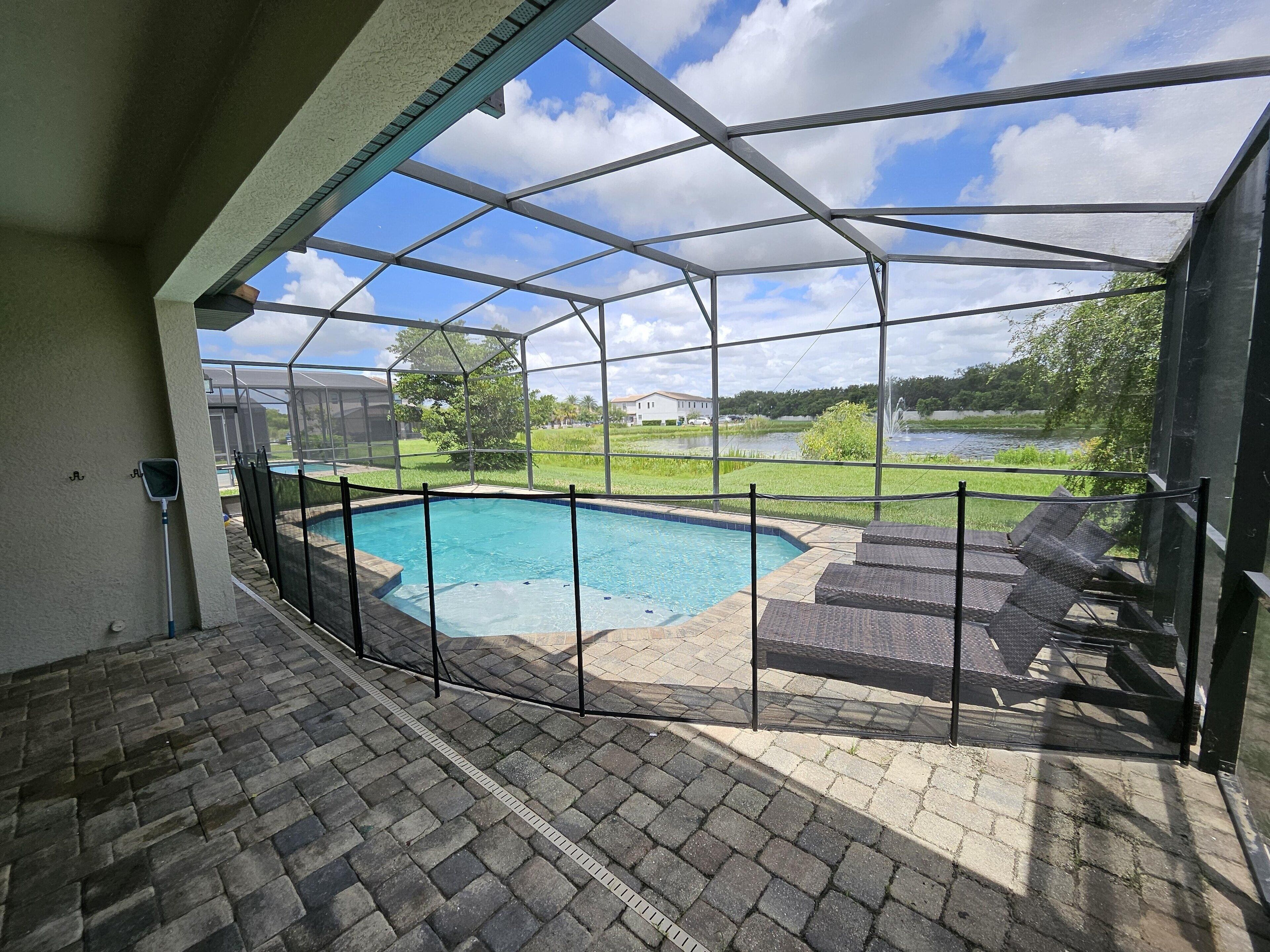 A covered outdoor area with a pool, a view of a lake, and a patio with chairs.