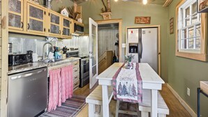 A kitchen with wooden cabinets, a refrigerator, a sink, and a dining table with a Christmas-themed tablecloth. - Creekbend 3 Bedroom Home (Sevierville)