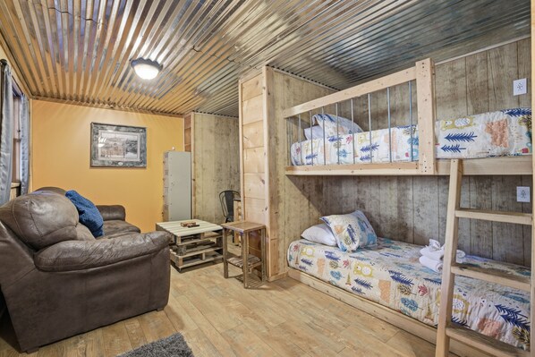 Une pièce rustique avec un lit superposé en bois, un canapé en cuir marron et une petite table en bois.