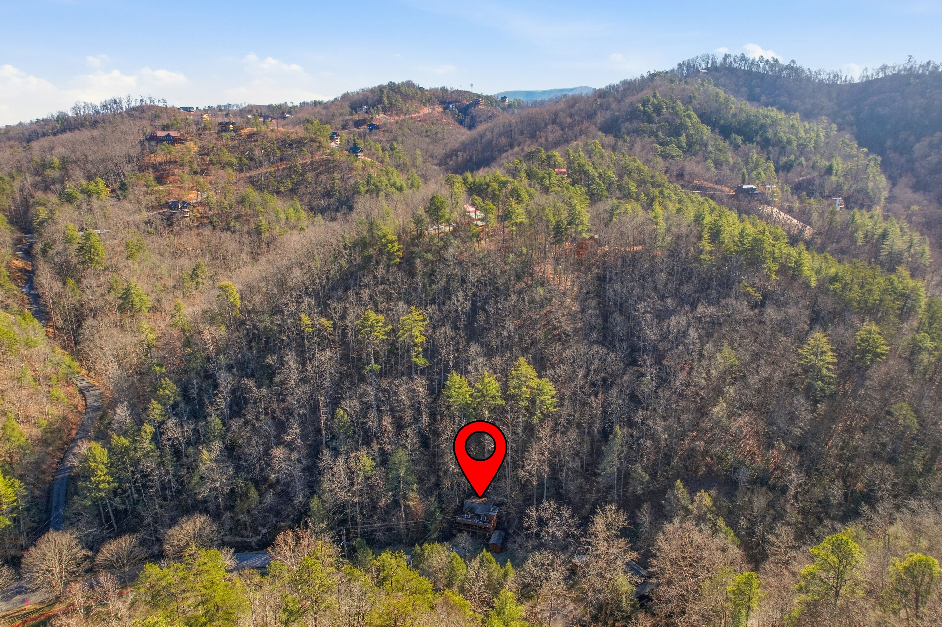 A mountainous landscape with scattered cabins and a red location marker.