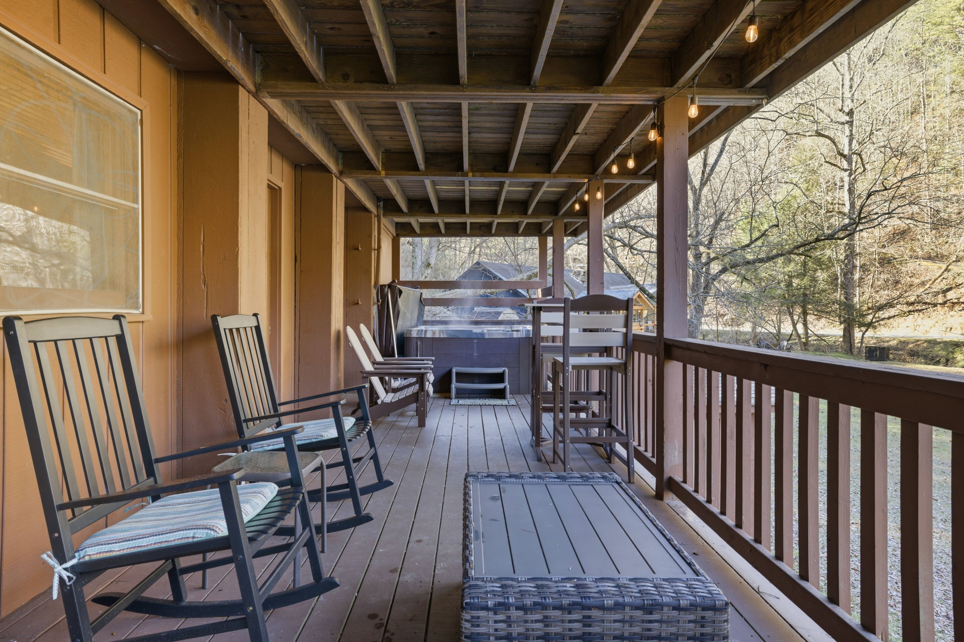 Eine überdachte Veranda mit Holzstühlen und einem Tisch, mit Blick auf einen bewaldeten Bereich.