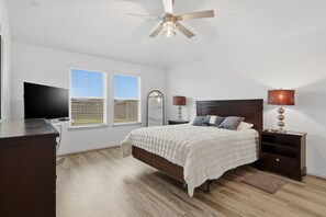 A bedroom with a bed, two bedside tables, a TV, and a ceiling fan. - Sunset Creek Sanctuary - Spacious Family Home 3 Bedroom Home (Richmond)