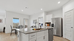 A modern kitchen with white cabinets, a stainless steel refrigerator, and a granite countertop. - Sunset Creek Sanctuary - Spacious Family Home 3 Bedroom Home (Richmond)