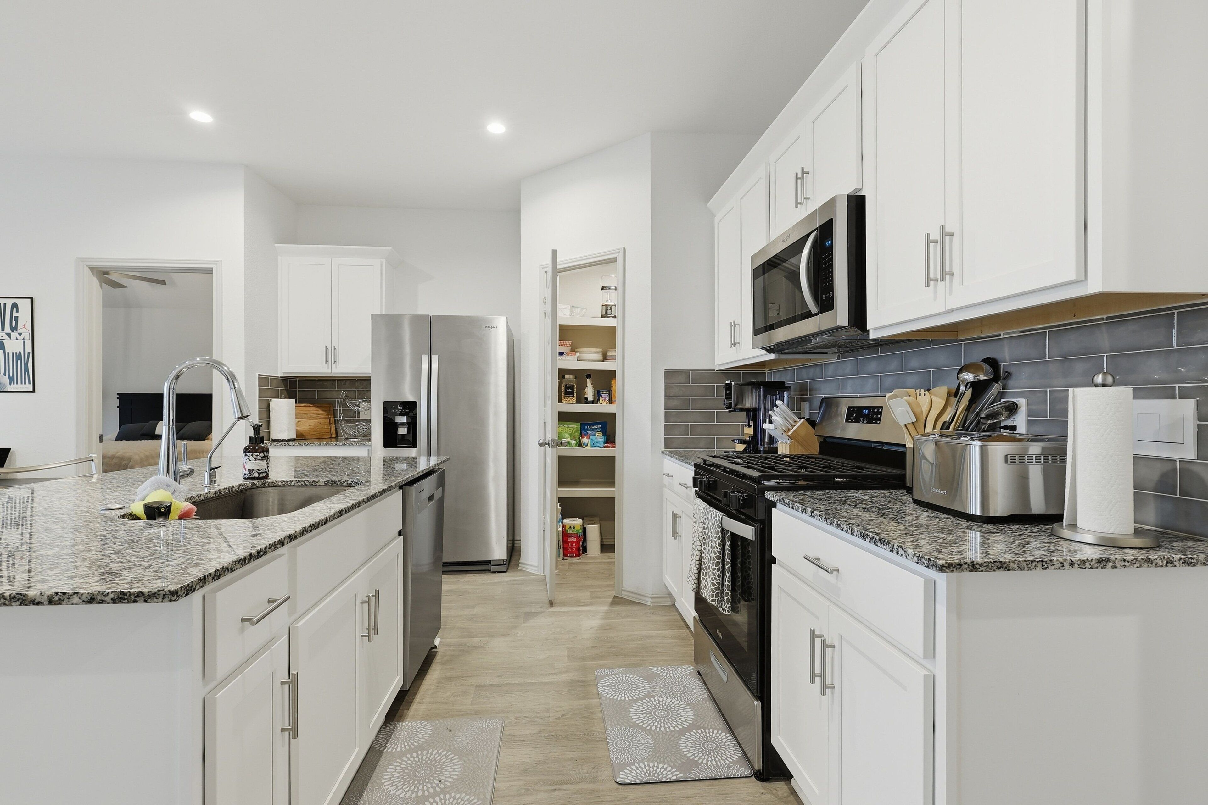 A modern kitchen with white cabinets, stainless steel appliances, and granite countertops.