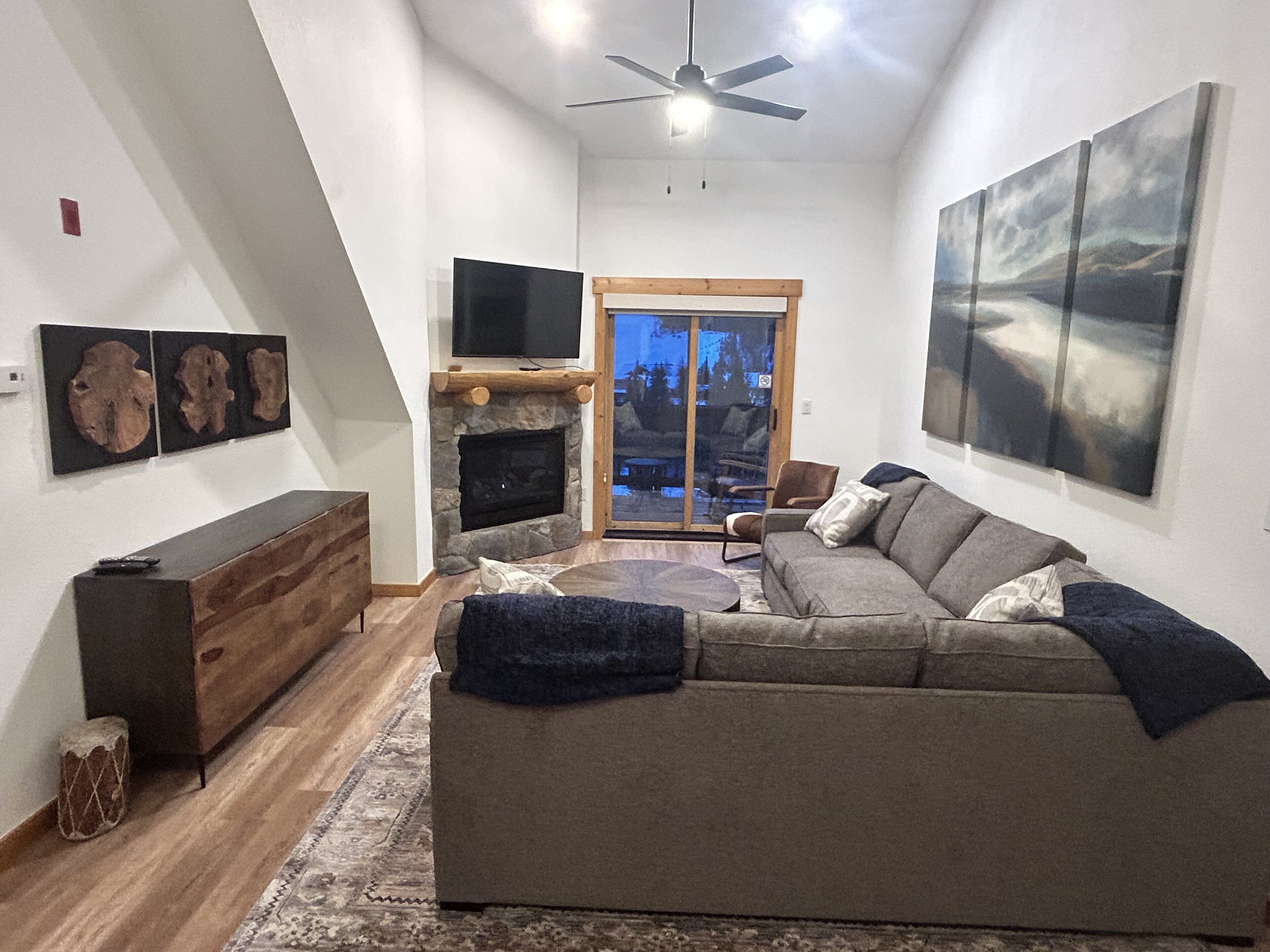 Ein Wohnzimmer mit Kamin, einer großen Couch, einem Fernseher und Kunstwerken an den Wänden.