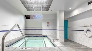 Un área de piscina con un letrero de profundidad de 9 metros, un letrero de emergencia 911 y una puerta azul.