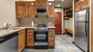 Una cocina con armarios de madera, un refrigerador de acero inoxidable, horno empotrado y lavavajillas.