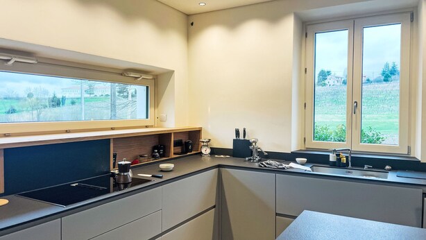 Een moderne keuken met een inbouwoven, een spoelbak en een raam met uitzicht op een groen landschap.