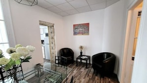 A modern living room with a glass coffee table, two black armchairs, a small side table, and a vase with flowers. - LE PARC Authentique Coeur de Ville Prox Park CLIM (Sète)