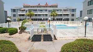 A multi-story hotel with a pool area, white fences, and a paved walkway. - Sea Cloisters 101e 3 Bedroom Condo (North Myrtle Beach)