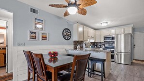 A modern kitchen with wooden cabinets, a central island, and a stainless steel refrigerator. - Sea Cloisters 101e 3 Bedroom Condo (North Myrtle Beach)