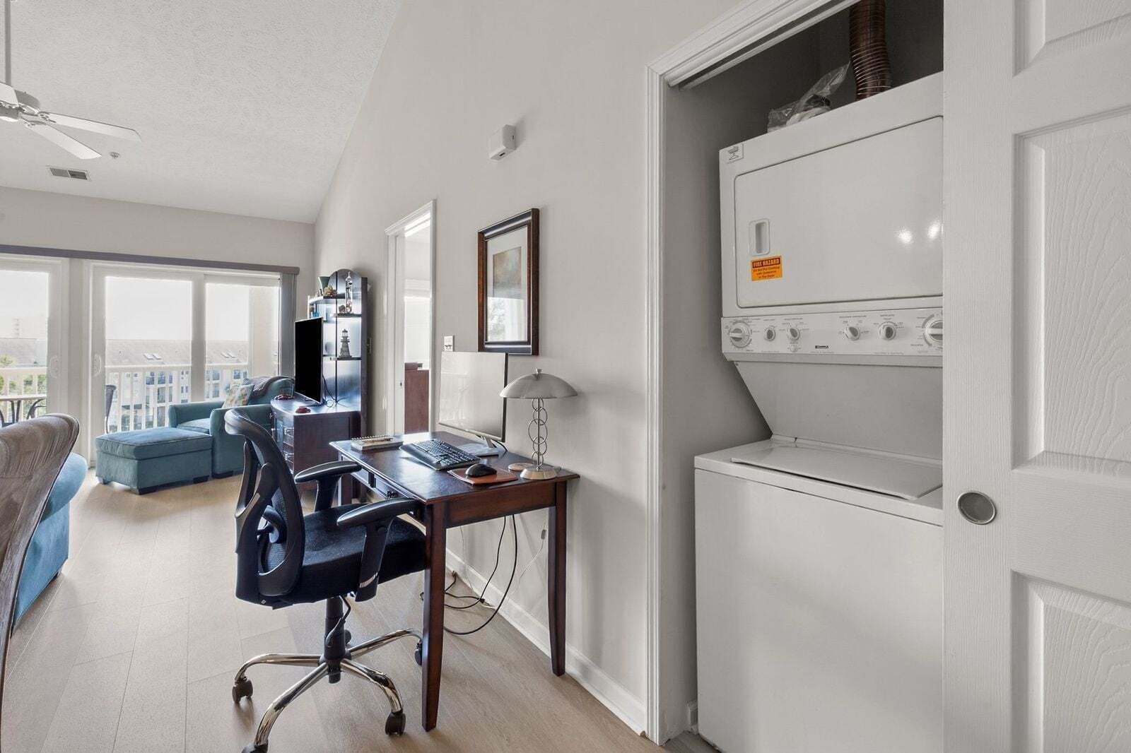 A modern apartment with a home office setup, a balcony, and a laundry room.