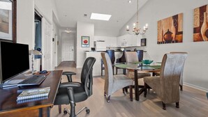 A modern kitchen with white cabinets, a dining area with a glass table and chairs, and a computer desk with a chair. - Ocean Keyes 2445 3 Bedroom Condo (North Myrtle Beach)
