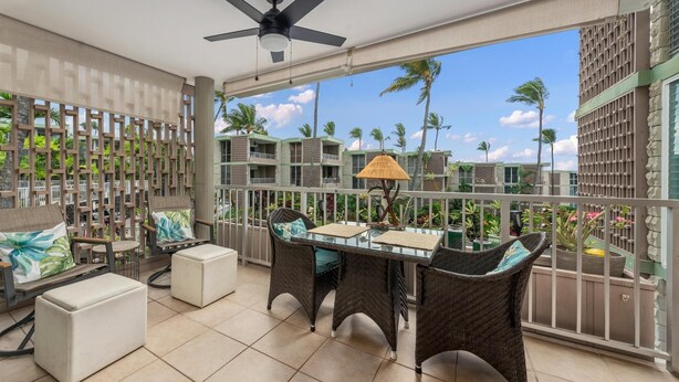 A balcony with wicker furniture, a glass table, and a ceiling fan. - Big Island Alii Villas 225 1 Bedroom Condo (Kailua-Kona)