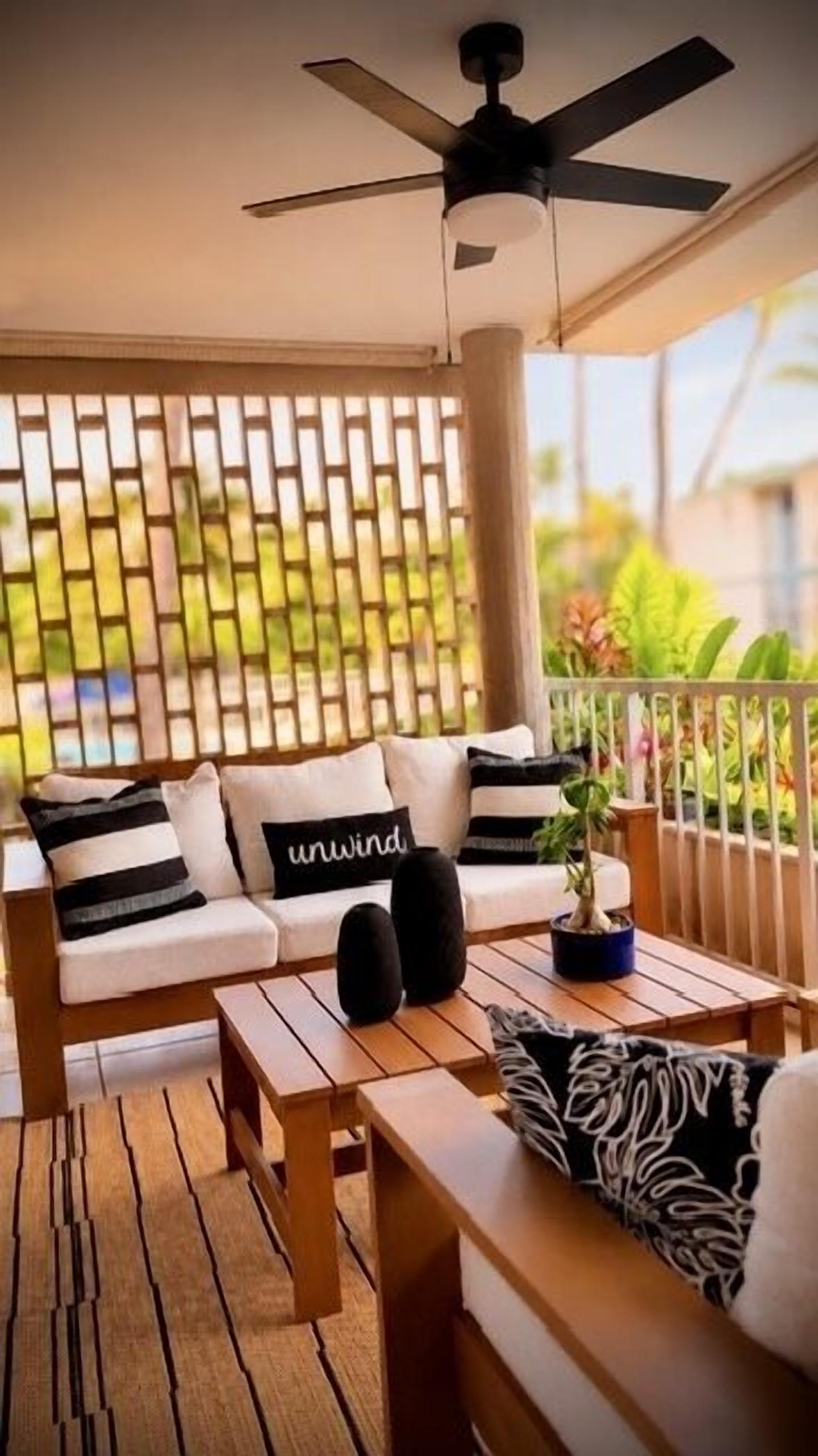 A balcony with a sofa, a table, and a ceiling fan.