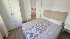 Un dormitorio con cama, armario y una silla.